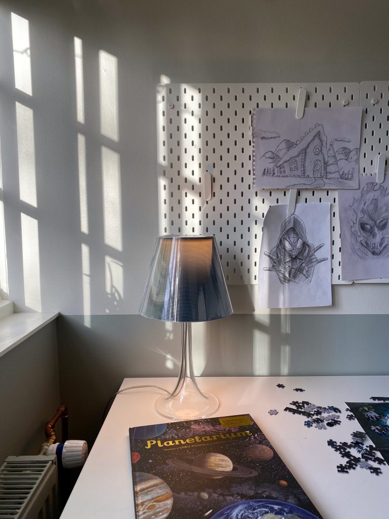Skrivebord med opslagsvæg og lampe og igangværende puslespil