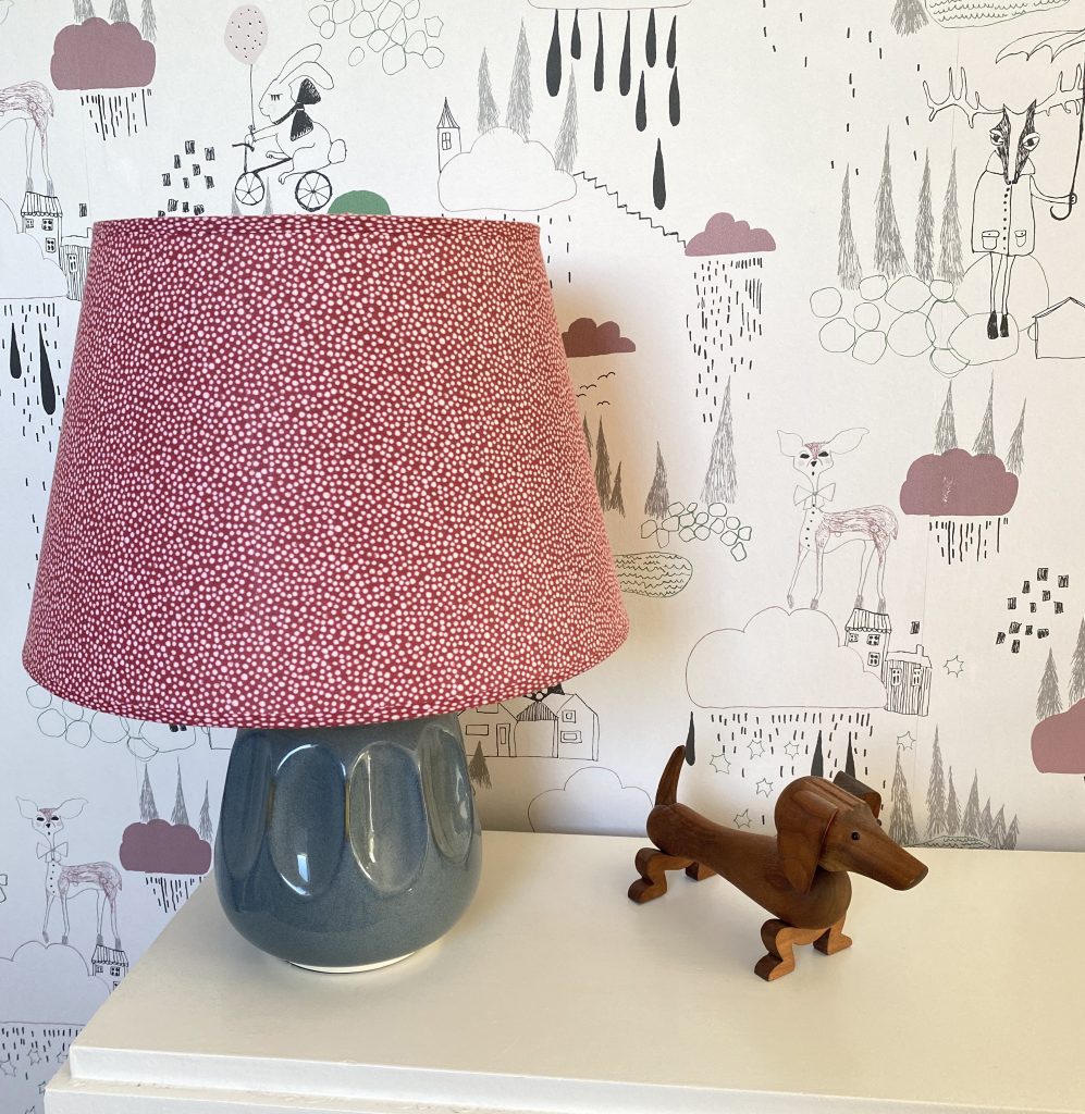 Efterbillede af børneværelse med nyt tapet, og rød lanpe