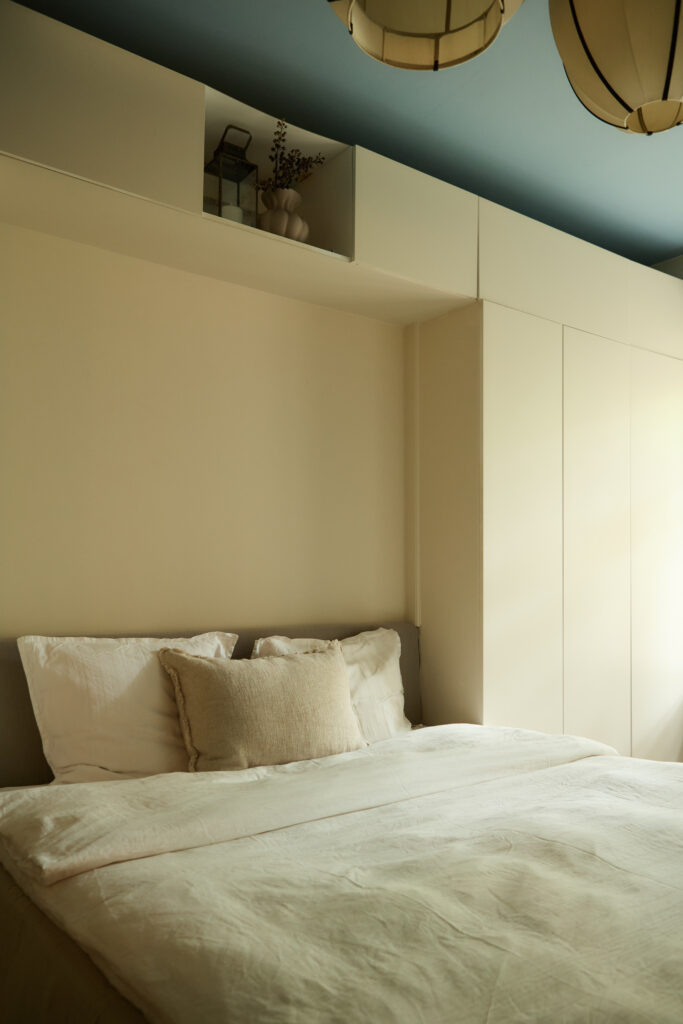 Soveværelse indrettet med fokus på opbevaring. Rolige og varme nuancer. Loft i blå kontrastfarve