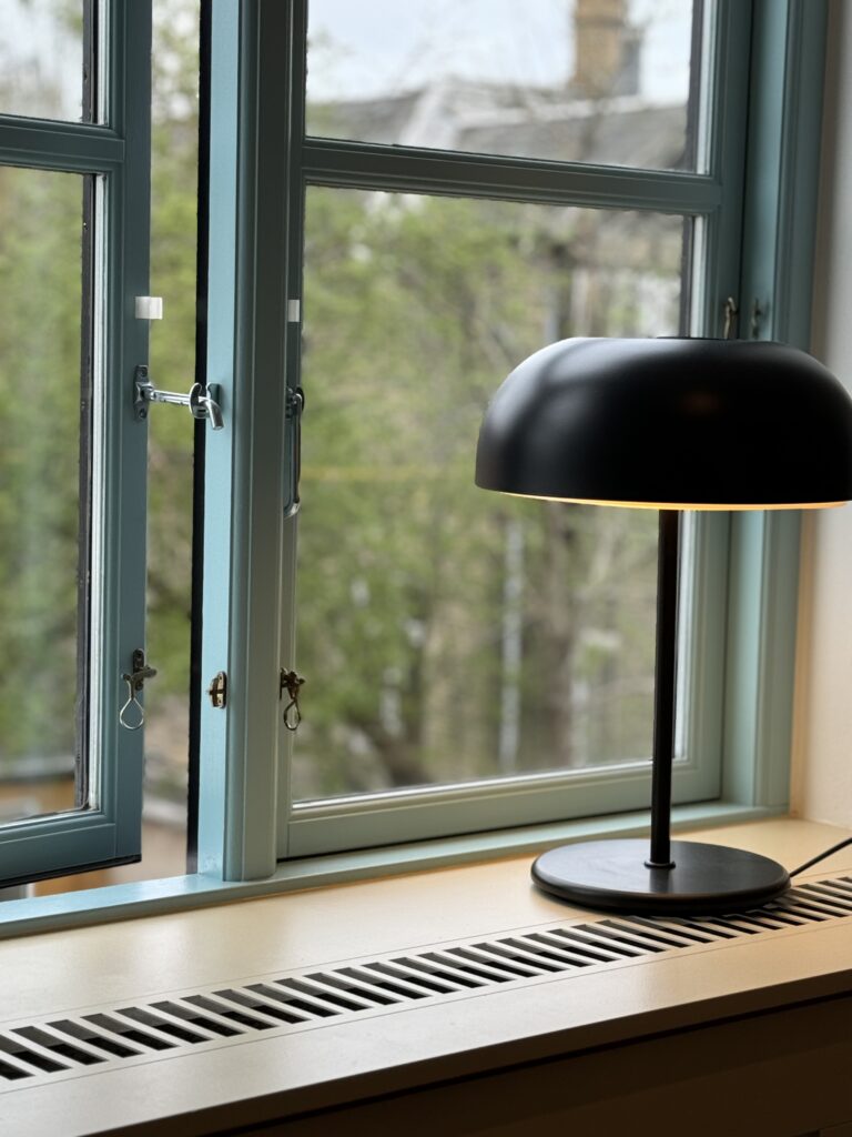 Indretning med blå-malede vinduesrammer og beige karm med en klassisk fin sort lampe